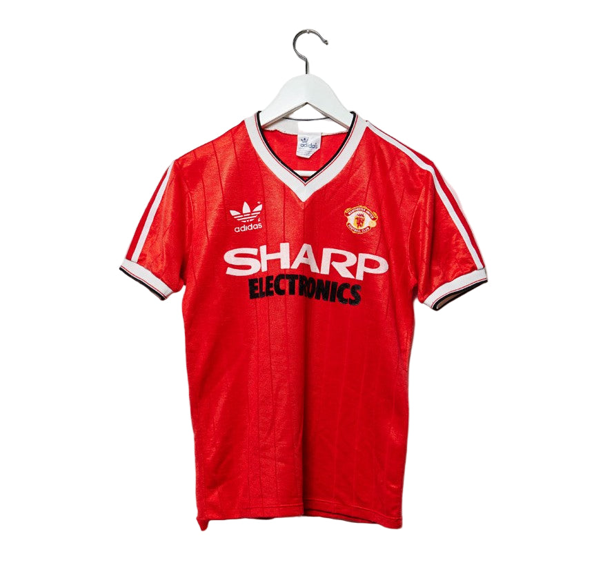 A red Manchester United soccer jersey from the 1982/83 home season, with 'Sharp Electronics' and 'adidas' logos.
