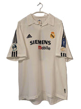 Real Madrid 2002/03 Home UCL Edition Jersey displayed on a hanger, predominantly white with sponsor logos and the Adidas logo.