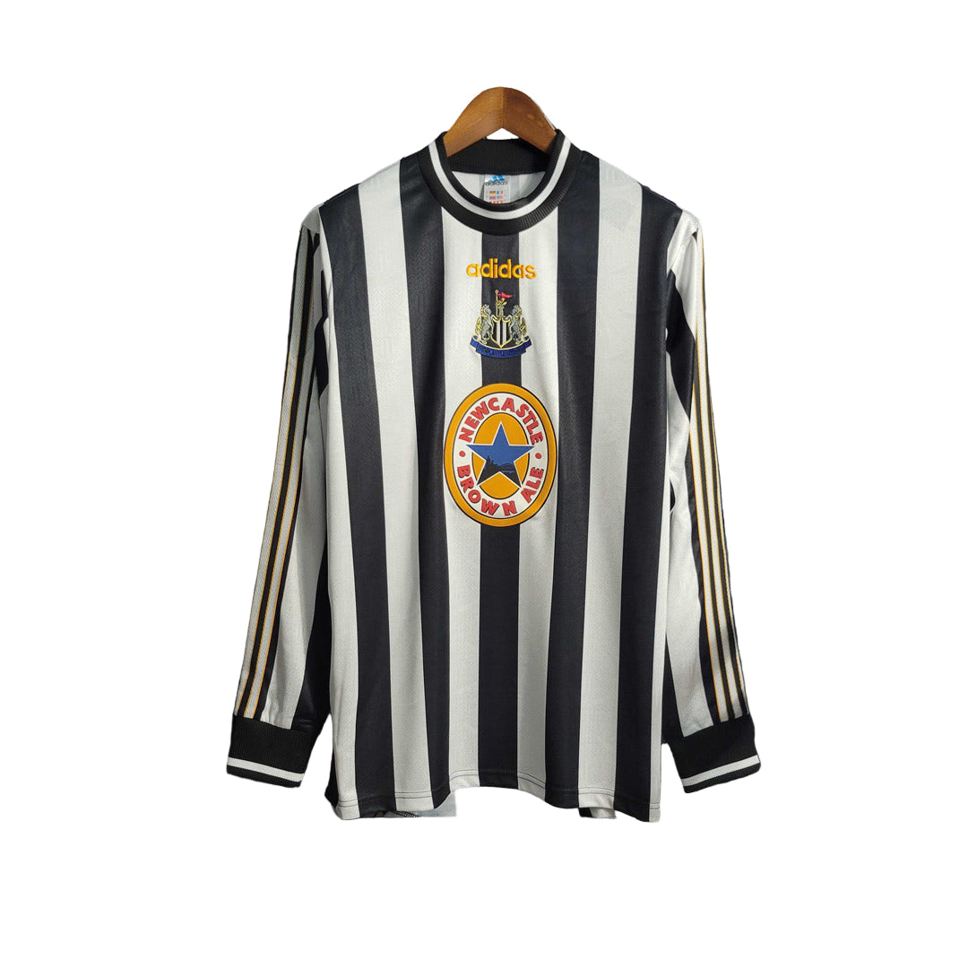 A black and white striped long sleeve soccer jersey displayed on a hanger, with Adidas logo and Newcastle United FC crest.